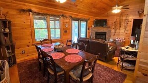 A wooden cabin interior with a dining table set for six, a fireplace, and a ceiling fan. - Big Rock Ridge - Easy Access for mountain views! (Murphy)
