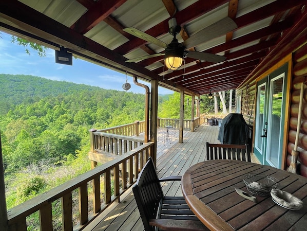 Una terraza de madera con vistas a una cadena montañosa boscosa.