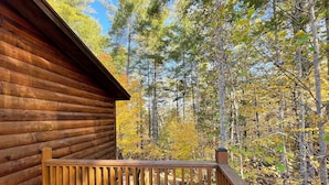 Eine Holzhütte mit einer Holzterrasse und Blick auf einen Wald.
