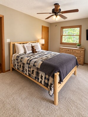 Une chambre à coucher avec un lit, un ventilateur de plafond, une fenêtre et une commode.