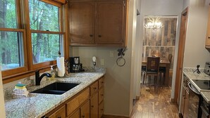 Eine Küche mit Holzausstattung, Granit Arbeitsplatten, einem Geschirrspüler und einem Teppich mit Katzenmotiv.