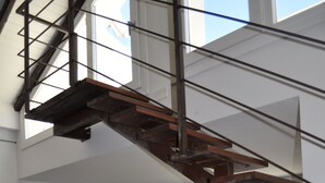 Ein Essbereich mit Holztisch und -stühlen, einer Steinwand und einer Treppe.