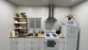 A compact kitchen with a gas stove, a microwave, and a sink. - Renovated studio 15 minutes from downtown San Diego (Lemon Grove)