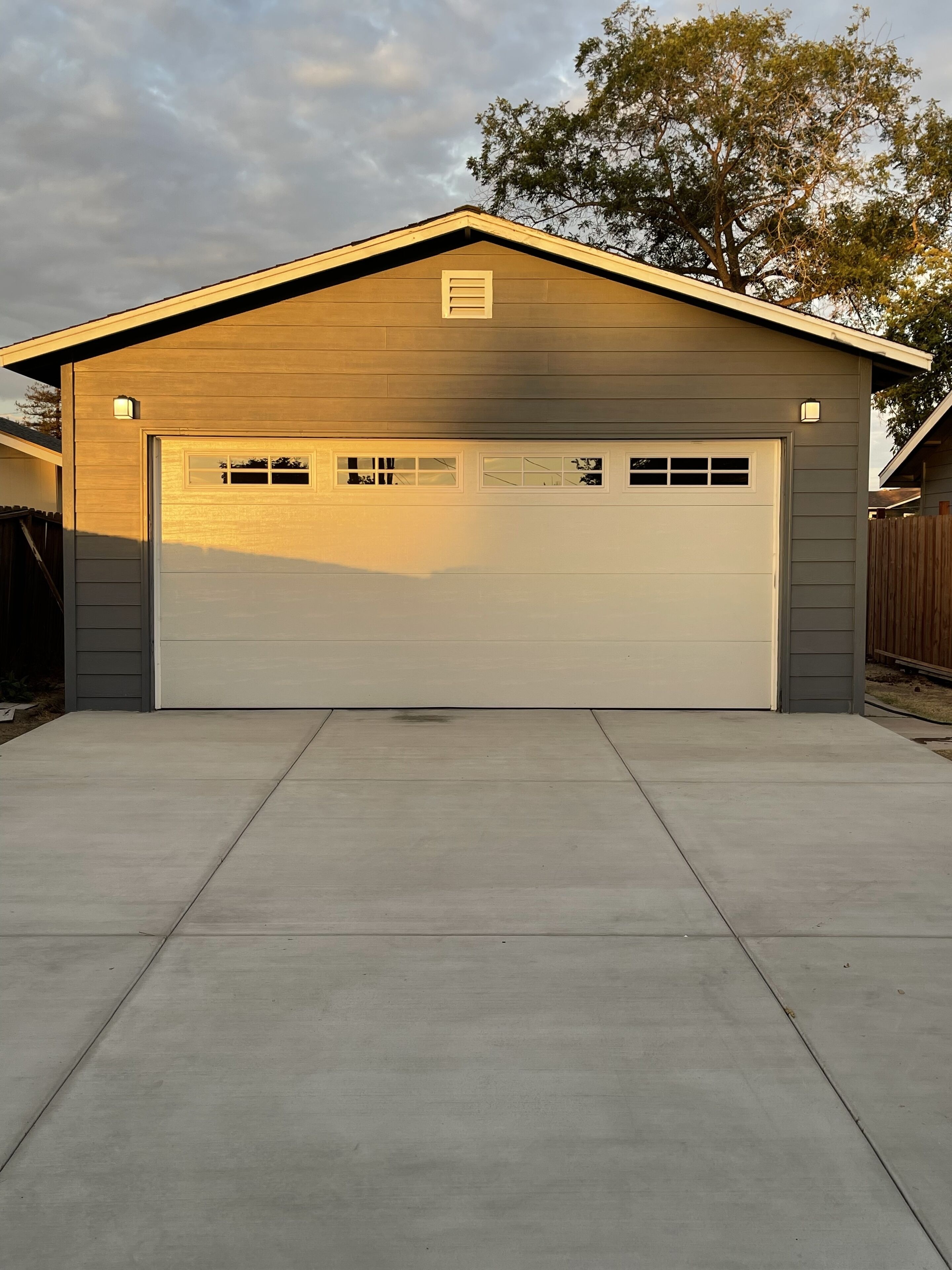 A single-story building with a garage door, a small window, and a light fixture above the door.