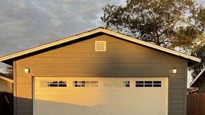 A single-story building with a garage door, a small window, and a light fixture above the door. - Renovated studio 15 minutes from downtown San Diego (Lemon Grove)