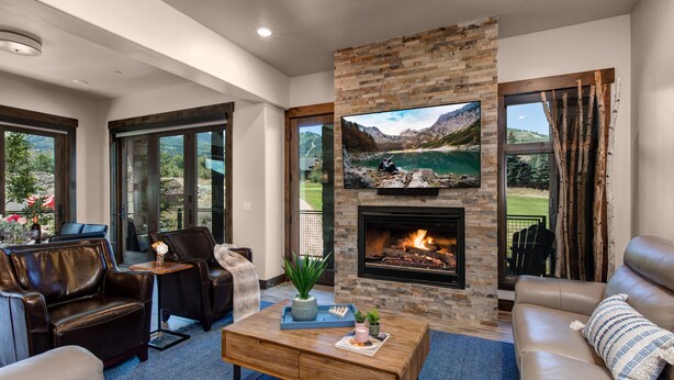 A modern living room with leather sofas, a fireplace, and a large TV mounted on a stone wall. - Interior Design, Luxury Community Amenities, Free Shuttle + Pet-Friendly! (Park City)