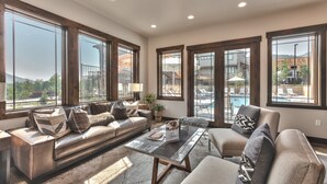 A spacious living room with a large window, a sofa, a coffee table, and a chair. - Interior Design, Luxury Community Amenities, Free Shuttle + Pet-Friendly! (Park City)