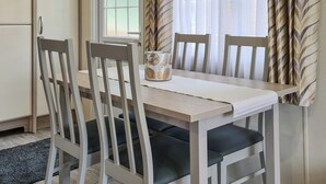 A dining area with a table, four chairs, a vase, and a microwave. - Castle Campbell View (Dollar)
