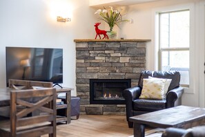 A living room with a stone fireplace, a television, and a leather sofa.