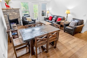 A living room with a fireplace, leather sofas, wooden coffee table, and a dining table.