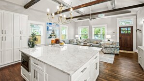 A spacious kitchen with a large island, white cabinetry, and a chandelier. - Heated Pool, King Beds, EV Charger, Garage & 3BR Sleep 7 · Walk to Beach (Galveston)