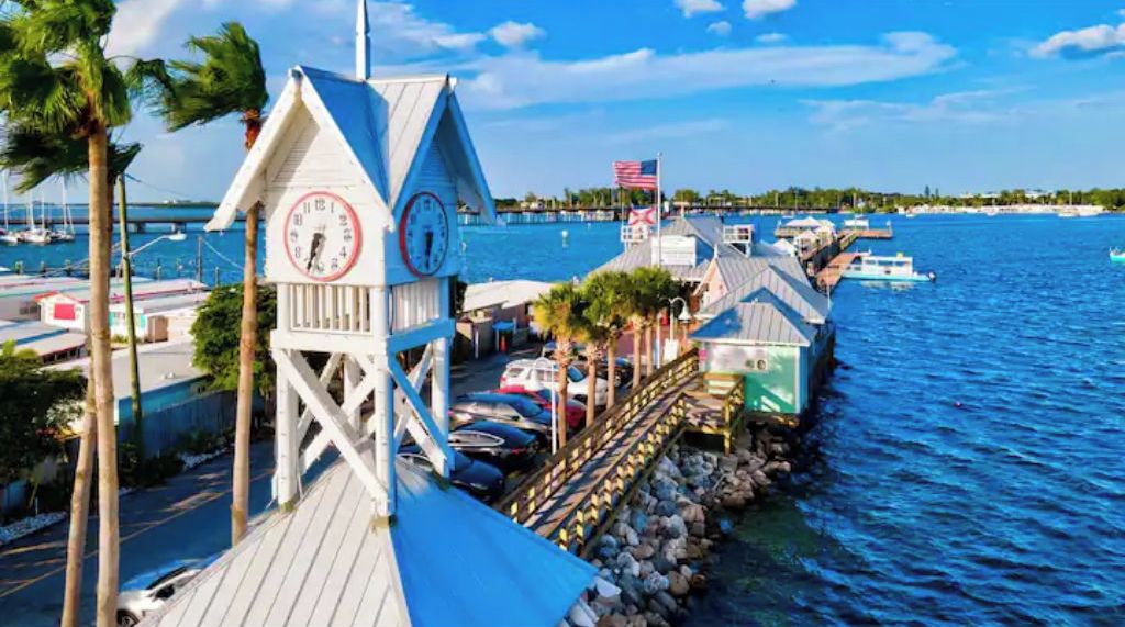A dock with a clock tower, boats, and a clear view of the water.