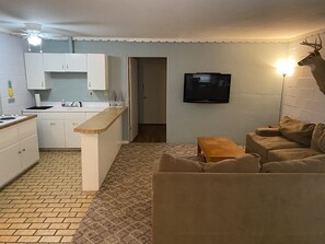 A compact living space with a kitchenette, a sofa, a small table, and a mounted television. - Waterfront with Sandy Shores! (Eufaula)