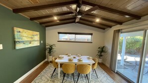 Un comedor con mesa blanca, sillas amarillas y un ventilador de techo.
