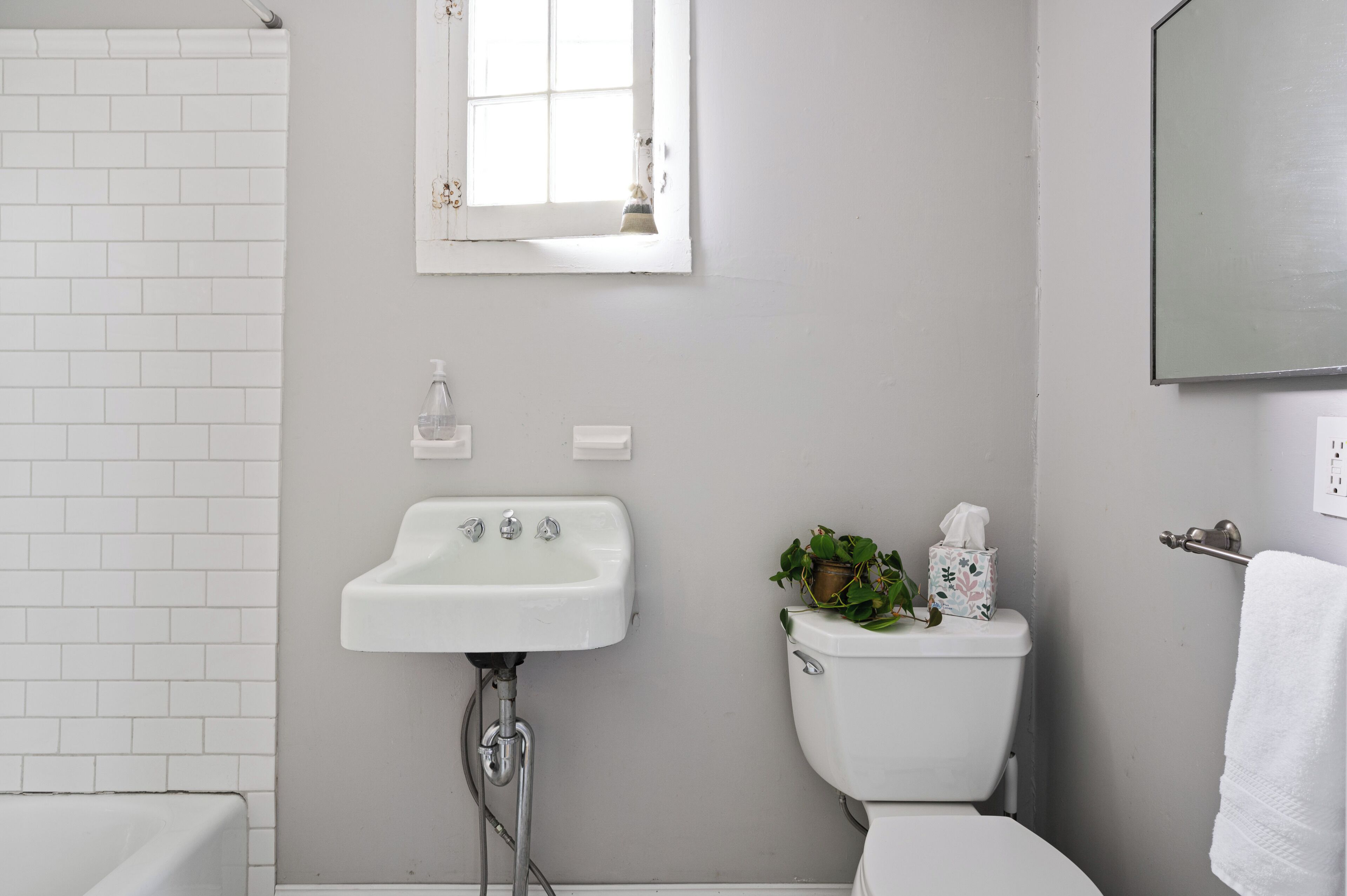 Un baño con lavamanos blanco, inodoro y espejo sobre el lavamanos.
