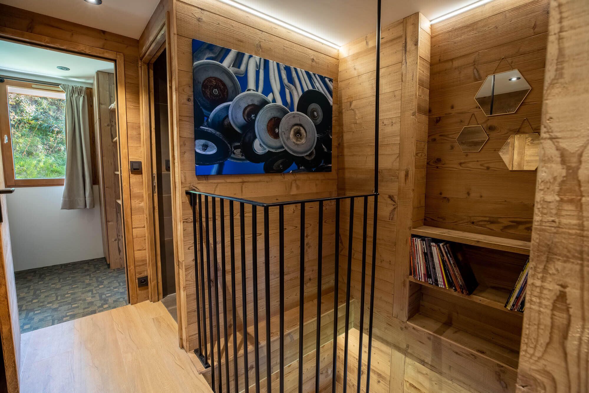 Un intérieur en bois orné d’un tableau représentant des roues, un escalier avec une rampe et une bibliothèque.