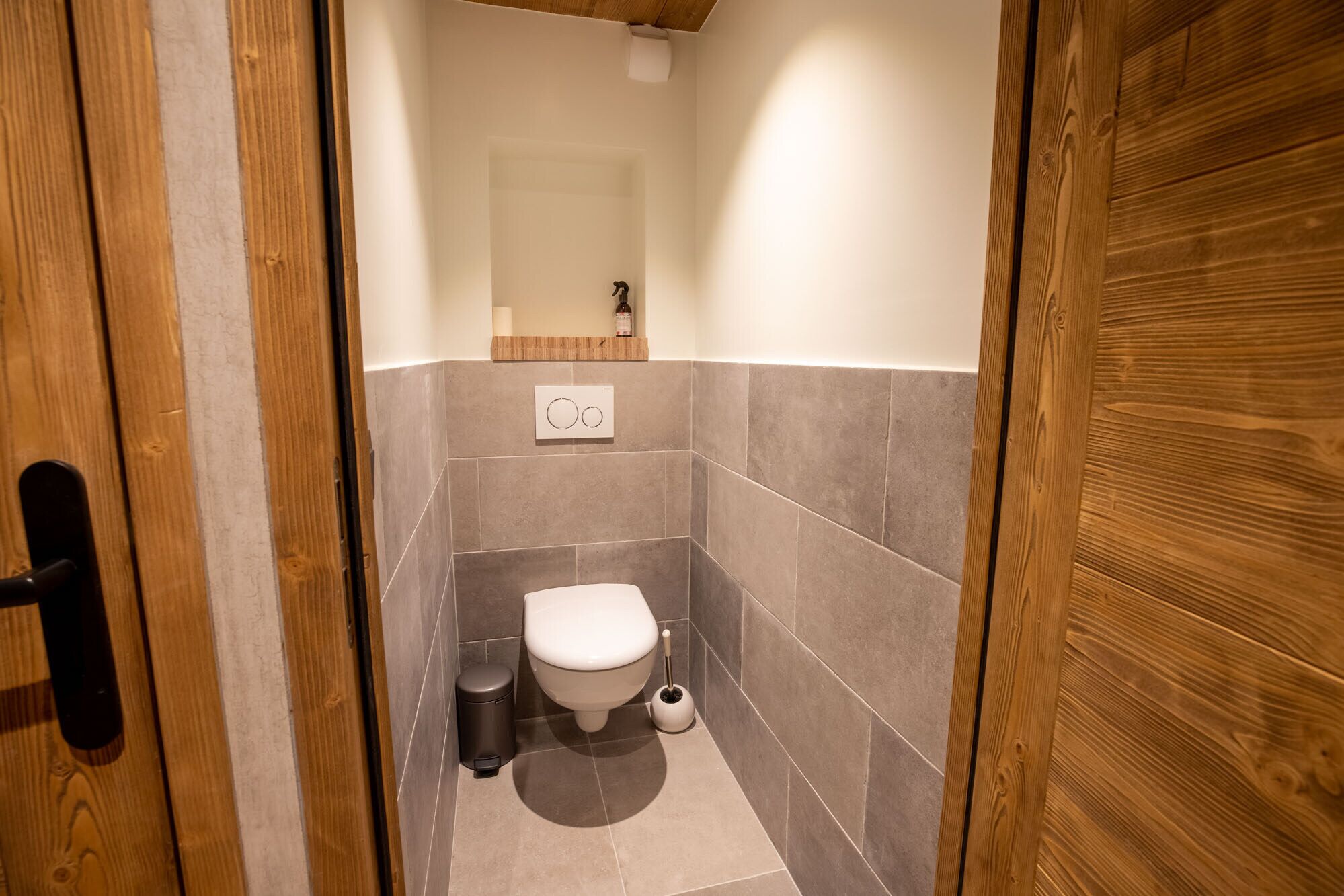 Une petite salle de bain compacte, équipée de toilettes, d’une poubelle et d’une brosse pour les toilettes.