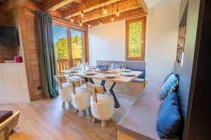 A cozy dining area with a wooden table set for four, flanked by fluffy white chairs, a cushioned bench, and a wooden cabinet.