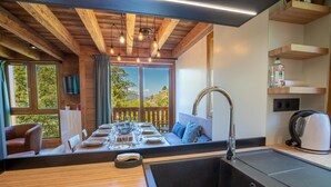 A modern kitchen with wooden beams, a dining area with a table set for four, and a view of the outdoors. - Hauts de Chantemouche 17 (Les Allues)