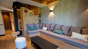 A cozy living room with a sectional sofa, a black bench, and a fluffy white sheep decoration. - Hauts de Chantemouche 17 (Les Allues)