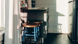 A narrow kitchen with wooden cabinets, a coffee machine, and a small table with blue chairs. - The Hangar at On The Rocks Container Scenic Lookout Mountain (Dade County)