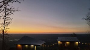 Two cabins with metal roofs, one with a visible signboard, set against a sunset backdrop with a distant view of a landscape. - The Hangar at On The Rocks Container Scenic Lookout Mountain (Dade County)