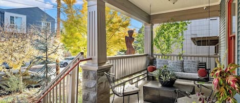 A covered porch with a stone column, outdoor seating, and a statue.