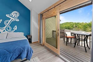 Une chambre avec un lit, une grande fenêtre et une vue sur une terrasse.