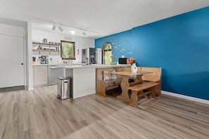 Una cocina moderna con una pared azul de acento, muebles de madera y un refrigerador empotrado.