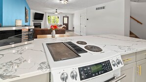 A kitchen with a white stove, a microwave, and a marble countertop.