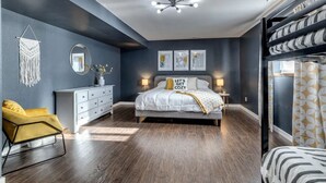 A modern bedroom with a bed, bedside tables, a dresser, a chair, and a ceiling light fixture.