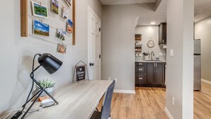 A modern kitchen with dark cabinets, a stainless steel refrigerator, and a hanging light fixture.