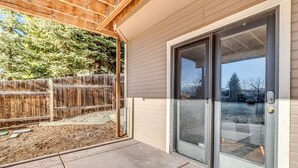 A house with a covered patio, a sliding glass door, and a wooden fence.