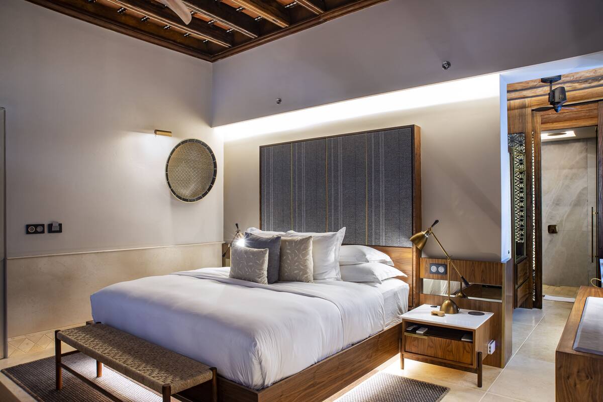A modern bedroom with a large bed, bedside table, and a wooden headboard.