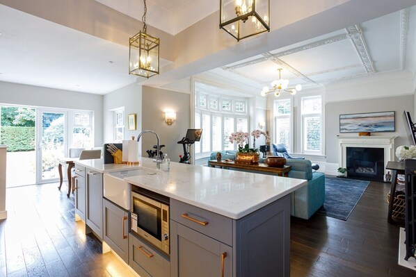 A spacious kitchen with a large island, modern appliances, and a dining area with a blue sofa and fireplace.