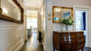 A hallway with a wooden floor, a vintage dresser, and a mirror with a gold frame. - Tranquil Apartment in Merseyside (Liverpool)