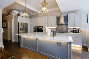 A modern kitchen with a large island, stainless steel appliances, and pendant lighting.
