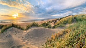 A beach with sand dunes and a person sitting on the dunes. - Tranquil Apartment in Merseyside (Liverpool)