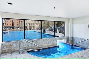 Swim laps in the indoor pool with a view of the outdoor pool through large windows.