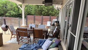 A covered patio area with a sofa, chairs, a table, and a grill. - Pet friendly country retreat (Tylden)