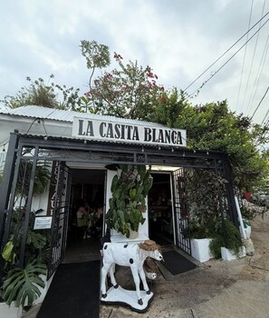 Une devanture de magasin avec une enseigne indiquant « LA CASITA BLANCA » et une statue de vache décorative placée à l’extérieur.