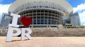 A modern building with a large circular auditorium and a prominent 'I ♥ PR' sign in front.