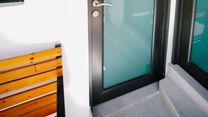 Una porta moderna amb un panell de vidre, una cadira de fusta i el número 6 a la paret.