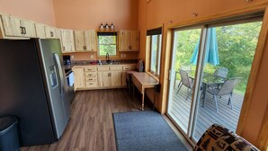 Una cocina compacta con armarios de madera, un refrigerador negro y una zona de comedor con mesa y sillas.