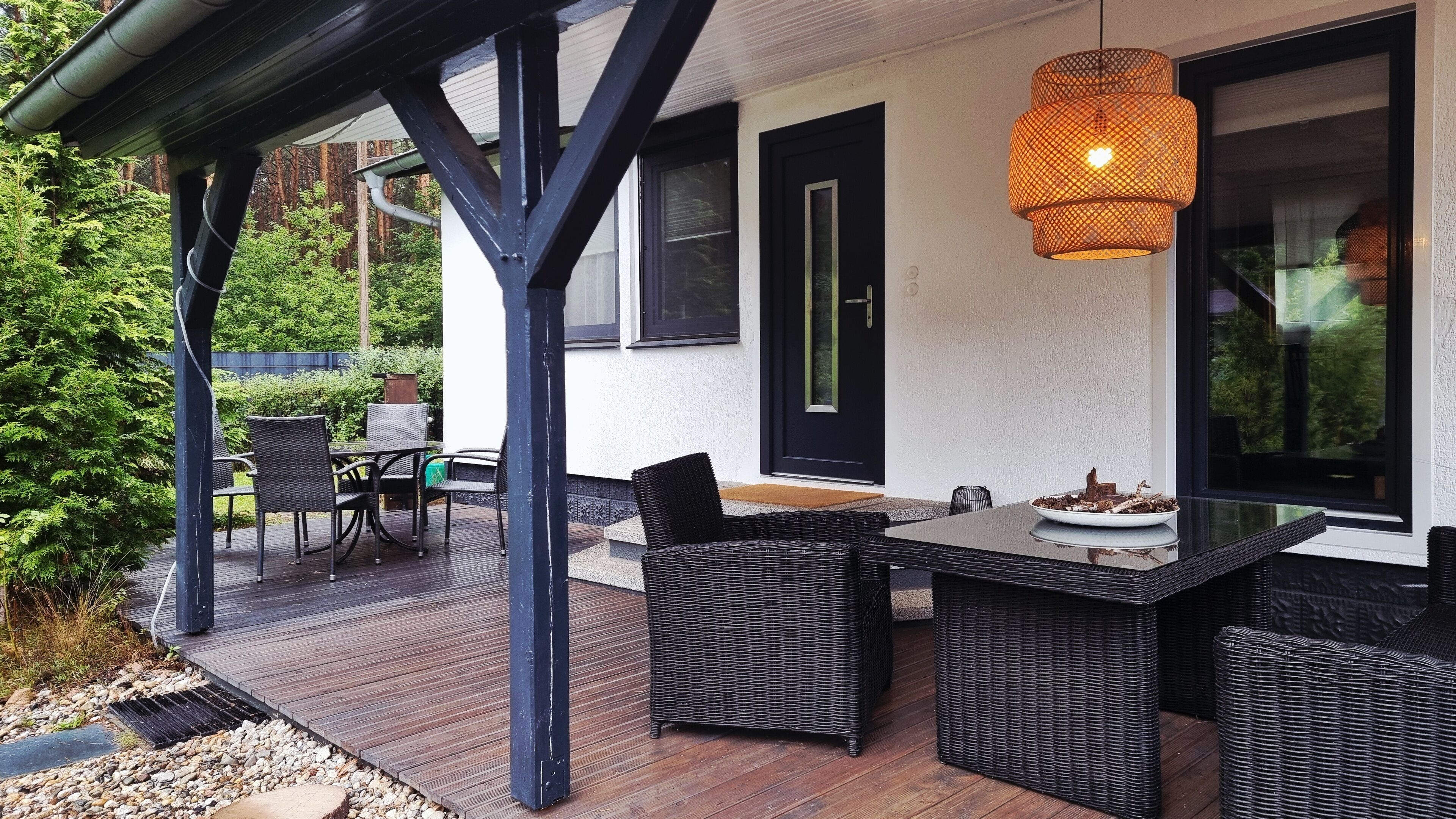 Eine Terrasse im Freien mit Tisch und Stühlen, einer Hängelampe und einer Tür mit Fenster.