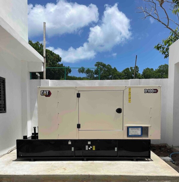 A large industrial air conditioning unit with the brand 'CAT' and model 'D100GC' mounted on a concrete base.