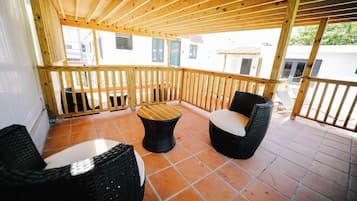 A covered outdoor seating area with wicker furniture and a tiled floor.