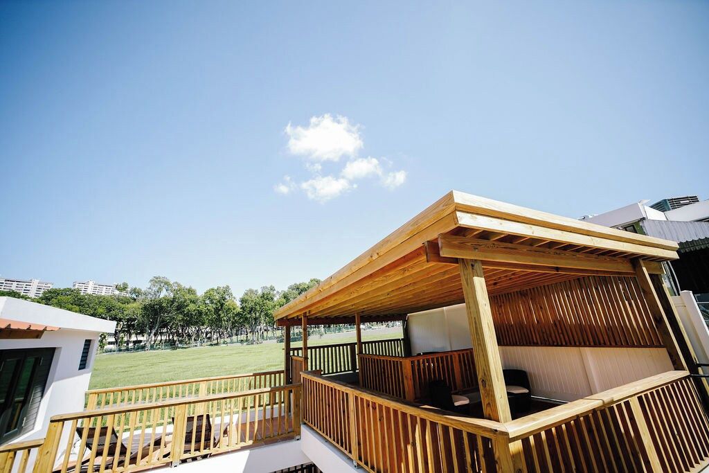 A wooden deck with a covered seating area overlooking a grassy field.