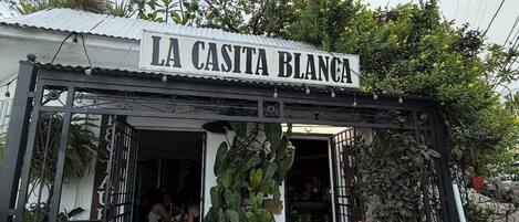 Una fachada con un letrero que dice 'LA CASITA BLANCA' y una estatua decorativa de vaca afuera.