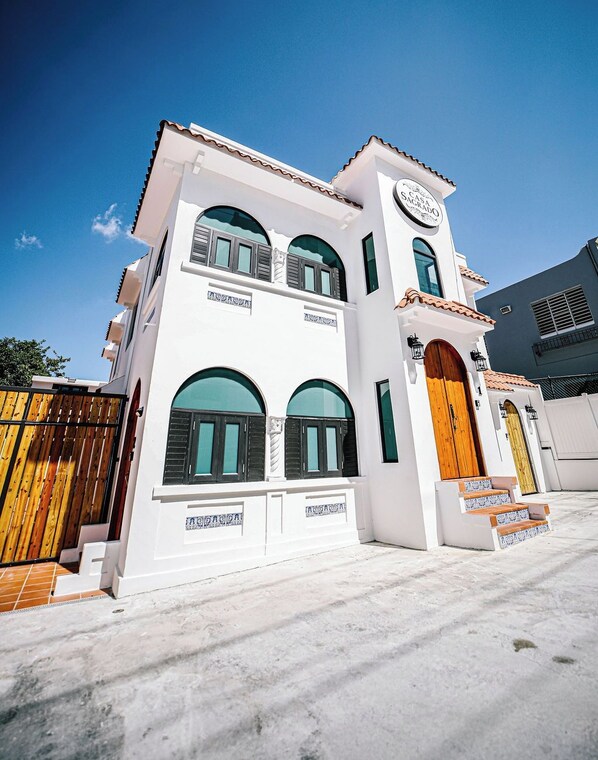 A two-story building with a white facade, a wooden door, and a sign that reads 'Casa a Sacrodo'.